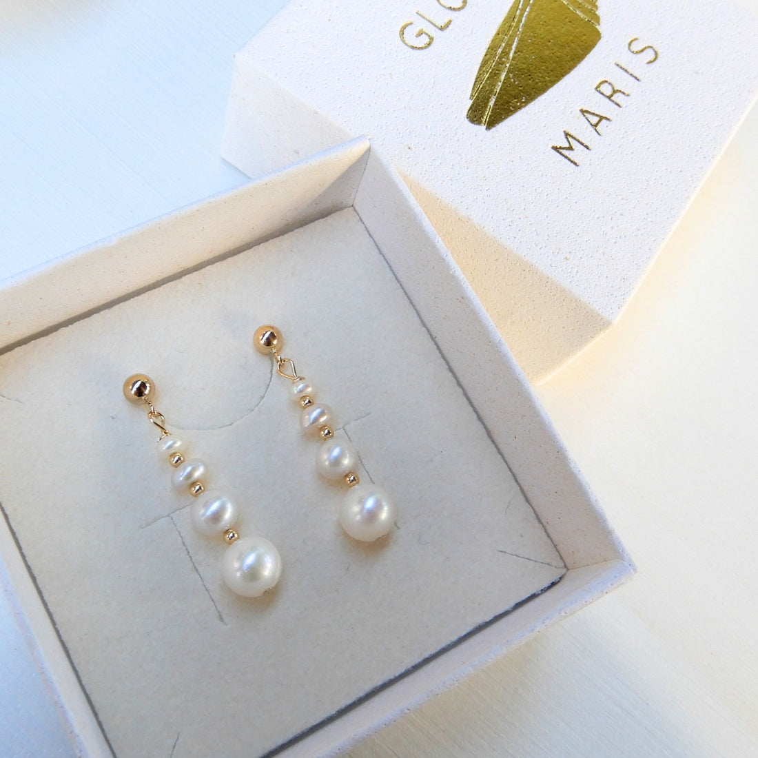 Zoetwater Parel oorstekers oplopend met goudkleurige tussenkralen.